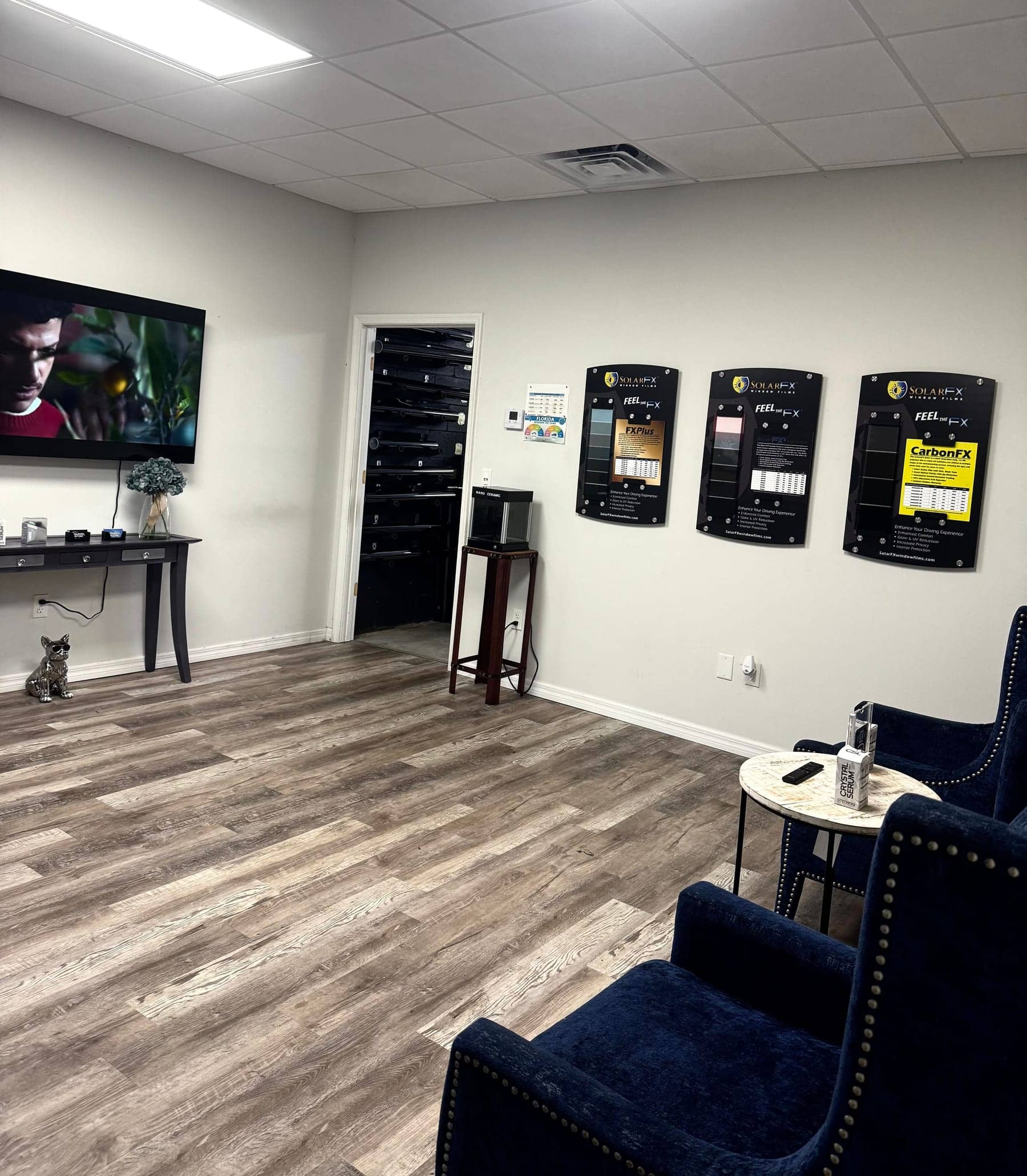 Equinox Tinting customer lounge with armchairs, a TV and film samples on the wall